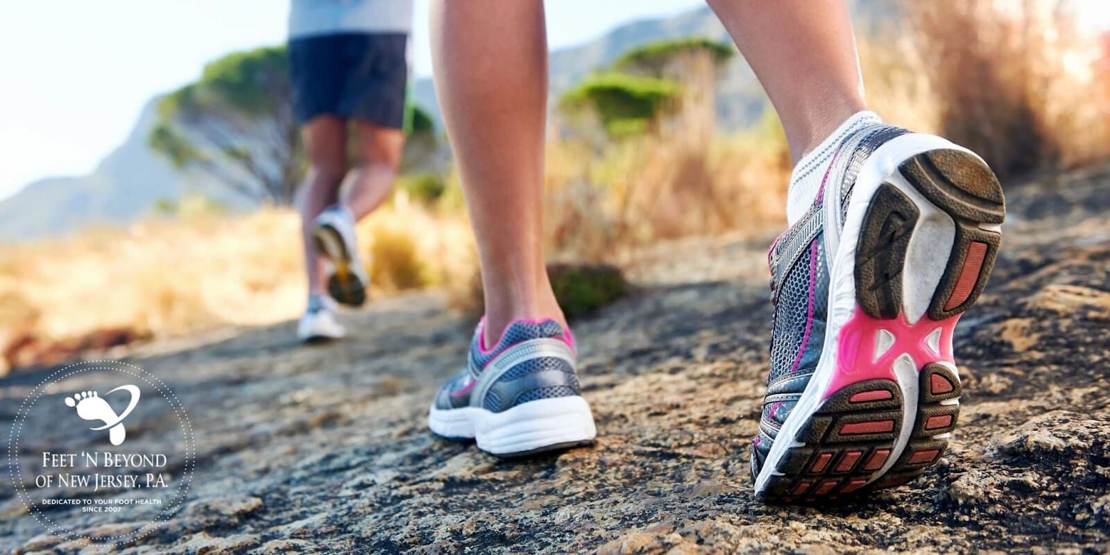 two people hiking on a rocky path, showcasing athletic shoes and active movement, emphasizing foot health.