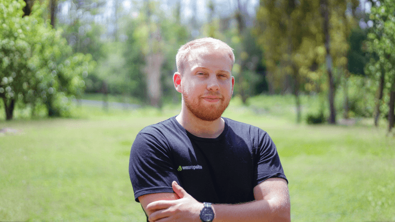 Augusto Boretti, founder of WeArePalta, stands confidently outdoors in front of a lush green background, symbolizing innovation.