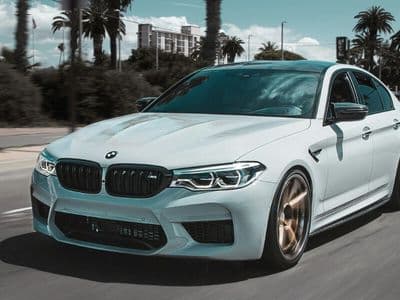 White BMW sedan driving on a city street, representing premium replacement vehicle rental options.