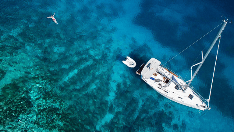Aerial view of a yacht and crystal-clear water, representing Go Sail Greece's luxurious, personalized sailing experiences across stunning Greek islands.