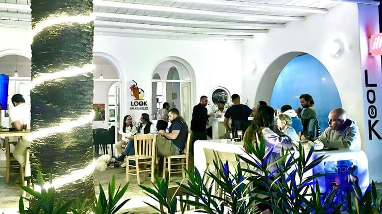 "Interior of Look Cafe & Billiards Bar in Drios, Paros, with people enjoying food and drinks in a lively atmosphere."
