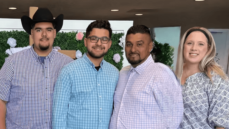"A family of four smiling together, dressed in plaid shirts, with a floral background reflecting a warm, supportive atmosphere."
