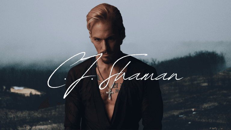 C.J. Shaman poses in dark clothing with cross necklace, name stylized across image, misty forest background.