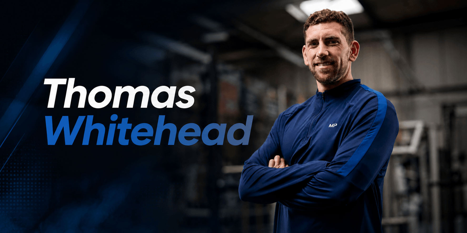 A man in a blue jacket smiling confidently in a gym setting