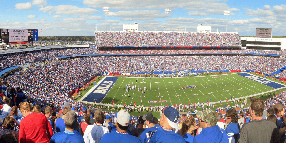 Panoramic view of a packed football stadium with fans cheering during a game