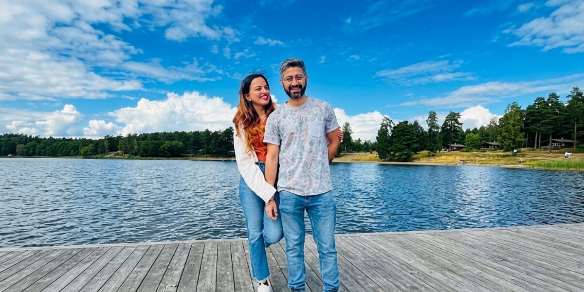 Payal Sood and companion standing on a lakeside dock under a blue sky in Sweden.