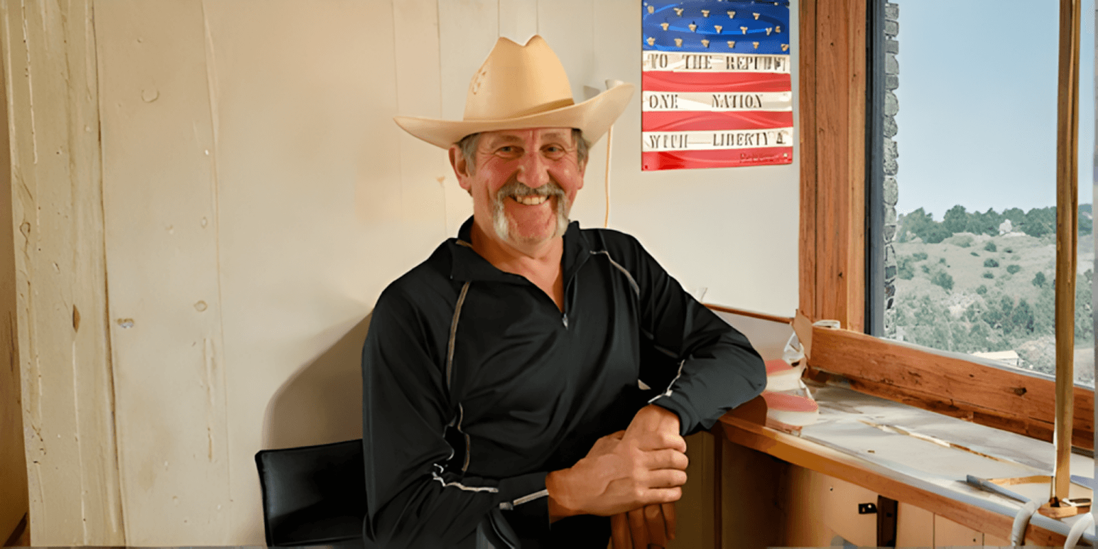 "David Hamel, U.S. Air Force veteran and marathoner, smiling in a cowboy hat, with an American flag in the background."