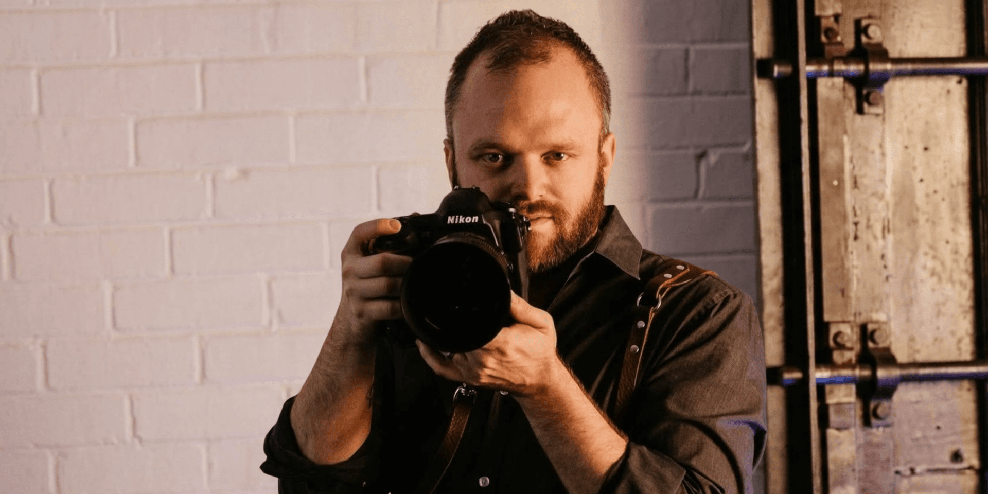 A photographer holding a Nikon camera, focused and ready to capture a shot