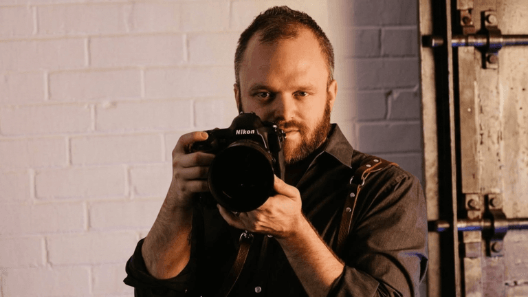 A photographer holding a Nikon camera, focused and ready to capture a shot