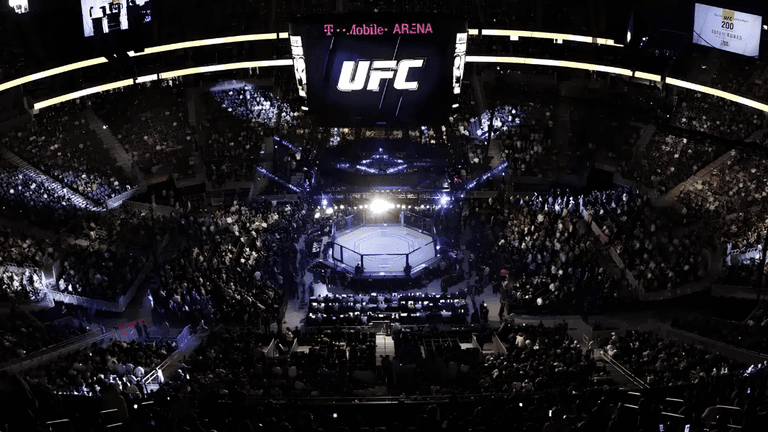 Aerial view of a packed UFC event at T-Mobile Arena with an illuminated octagon