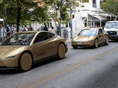 Two gold-colored electric cars on a city street with pedestrians and vehicles nearby