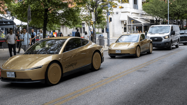 Two gold-colored electric cars on a city street with pedestrians and vehicles nearby