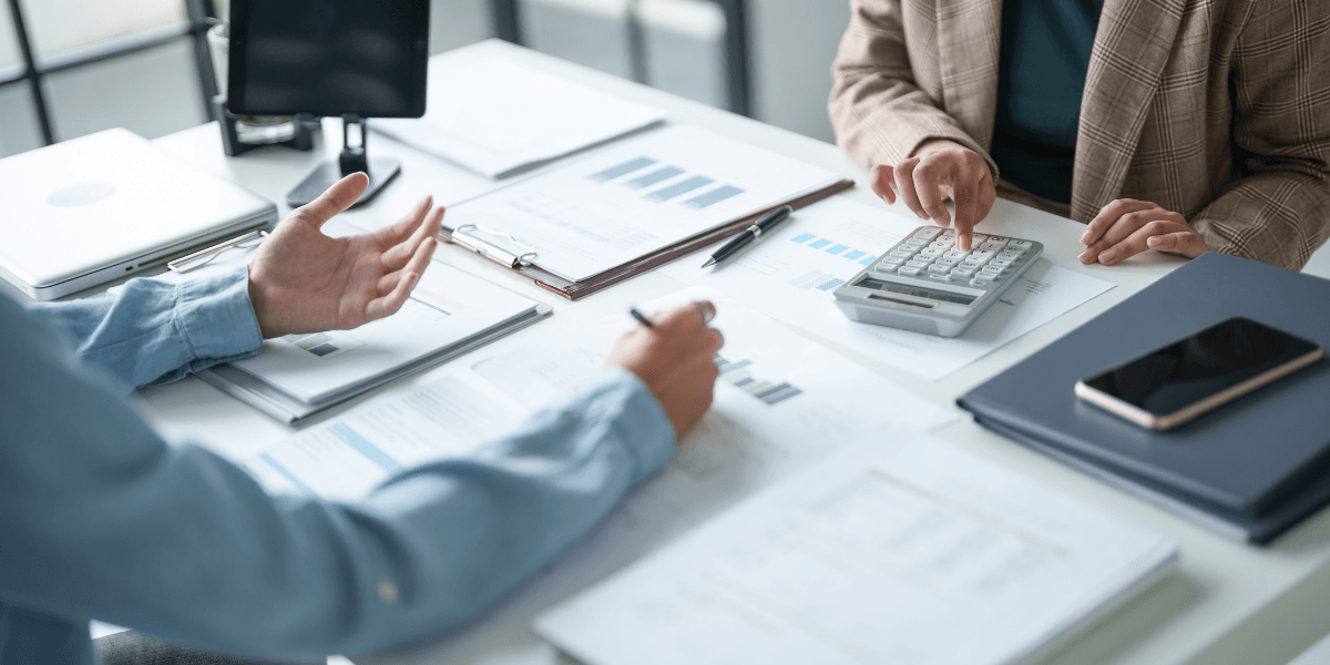Two people discussing finances with a calculator and paperwork on a table