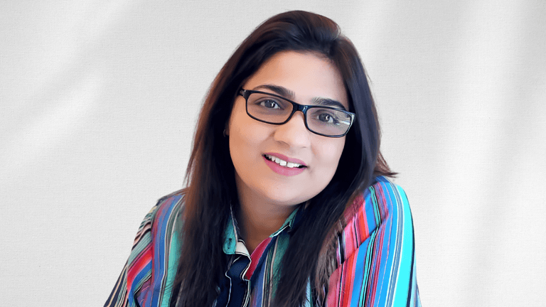 A woman with glasses and colorful striped shirt smiling against a light background