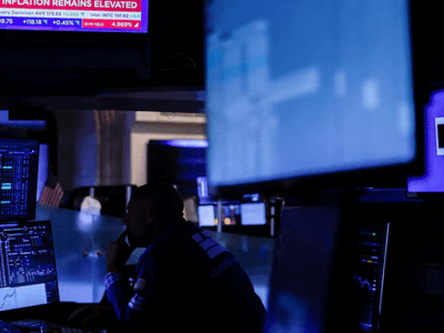 Trader monitoring stock market data amid blue-lit screens in a trading room
