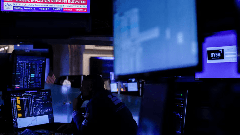 Trader monitoring stock market data amid blue-lit screens in a trading room