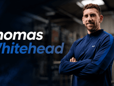 A man in a blue jacket smiling confidently in a gym setting