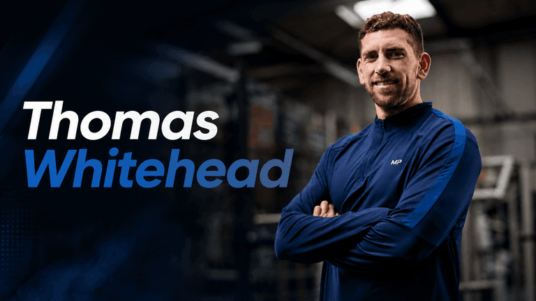 A man in a blue jacket smiling confidently in a gym setting