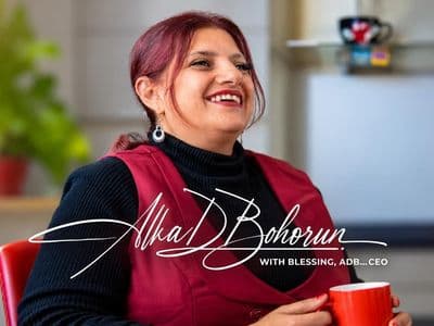 A woman smiling while holding a red cup in a bright indoor setting