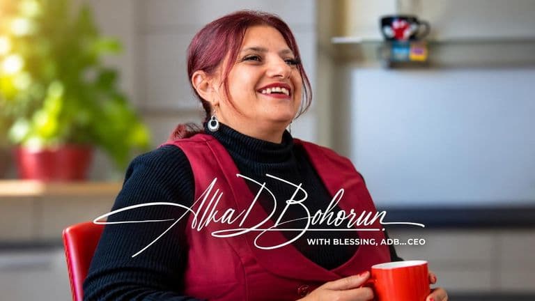 A woman smiling while holding a red cup in a bright indoor setting