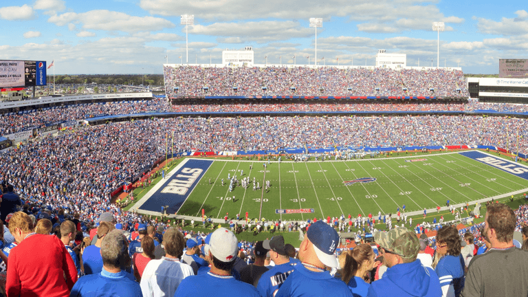 Panoramic view of a packed football stadium with fans cheering during a game