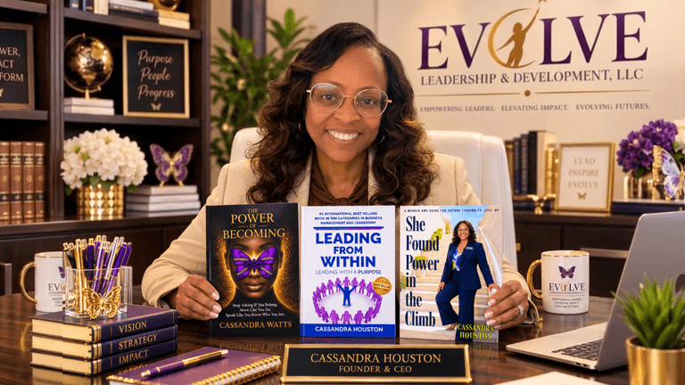 A woman sits at a desk with her books, promoting her leadership development business.