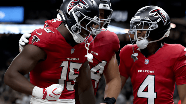 Atlanta Falcons players celebrate a touchdown on the field, wearing red jerseys.