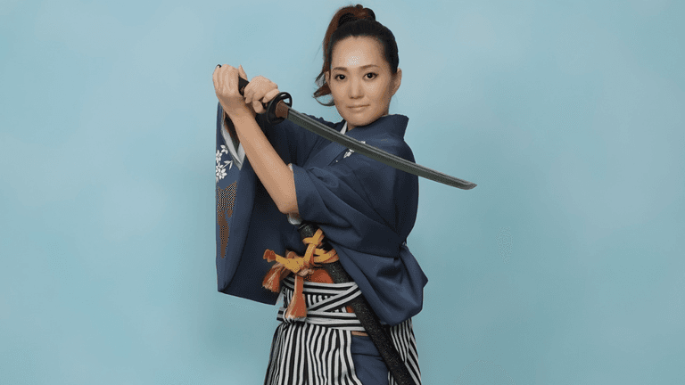 Woman in traditional attire holding a katana in poised stance against blue background