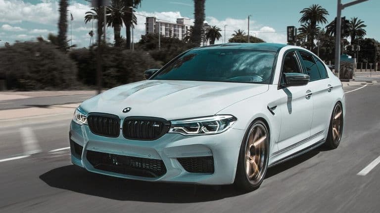 White BMW sedan driving on a city street, representing premium replacement vehicle rental options.