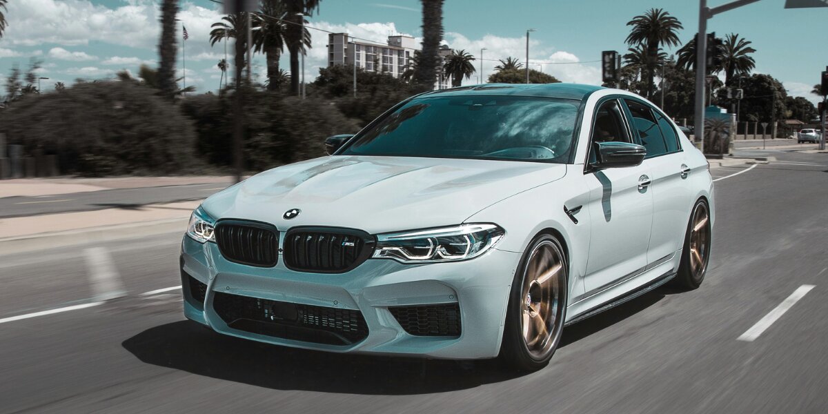 White BMW sedan driving on a city street, representing premium replacement vehicle rental options.