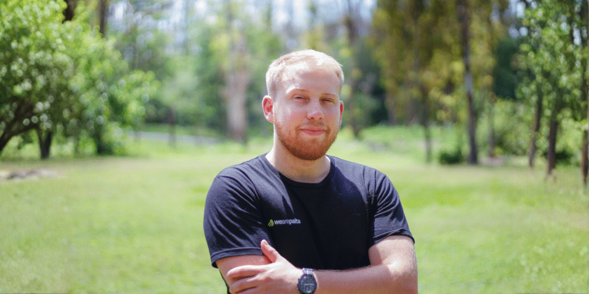 Augusto Boretti, founder of WeArePalta, stands confidently outdoors in front of a lush green background, symbolizing innovation.