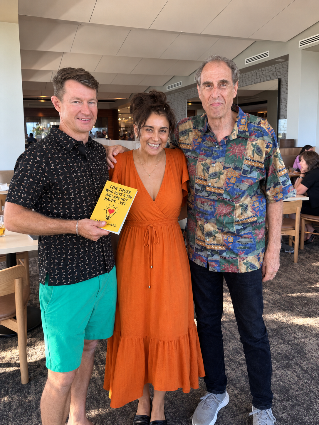 Daniela Jines with colleagues holding her workplace happiness book.