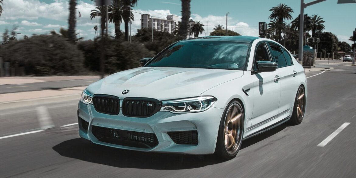 White BMW sedan driving on a city street, representing premium replacement vehicle rental options.