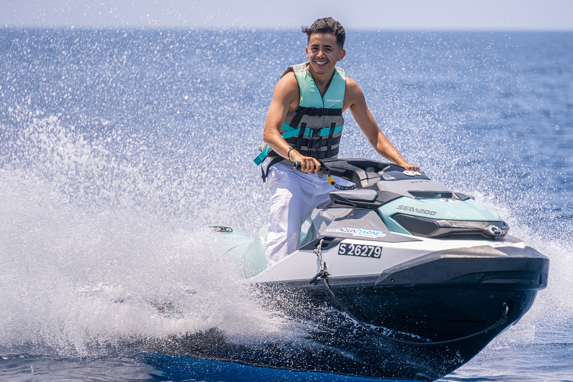 Rider wearing a life jacket operates an Aquamarine Sea-Doo jet ski across open water.